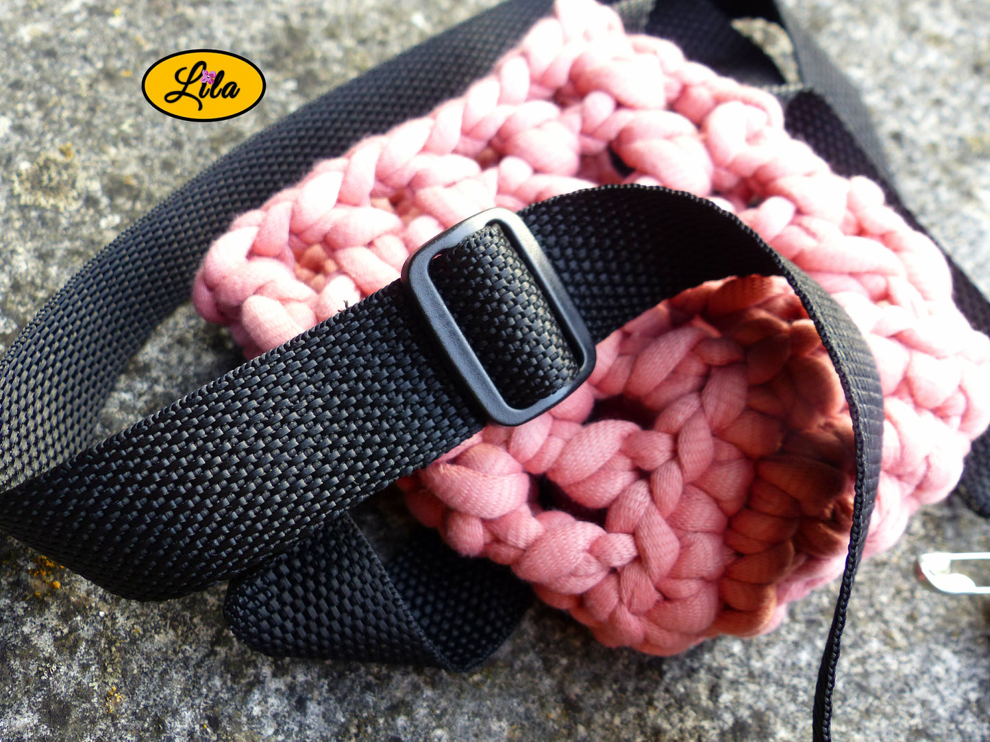 Zoom sur la sangle noire posée sur un porte-gobelet crocheté rose style festival et artisanal