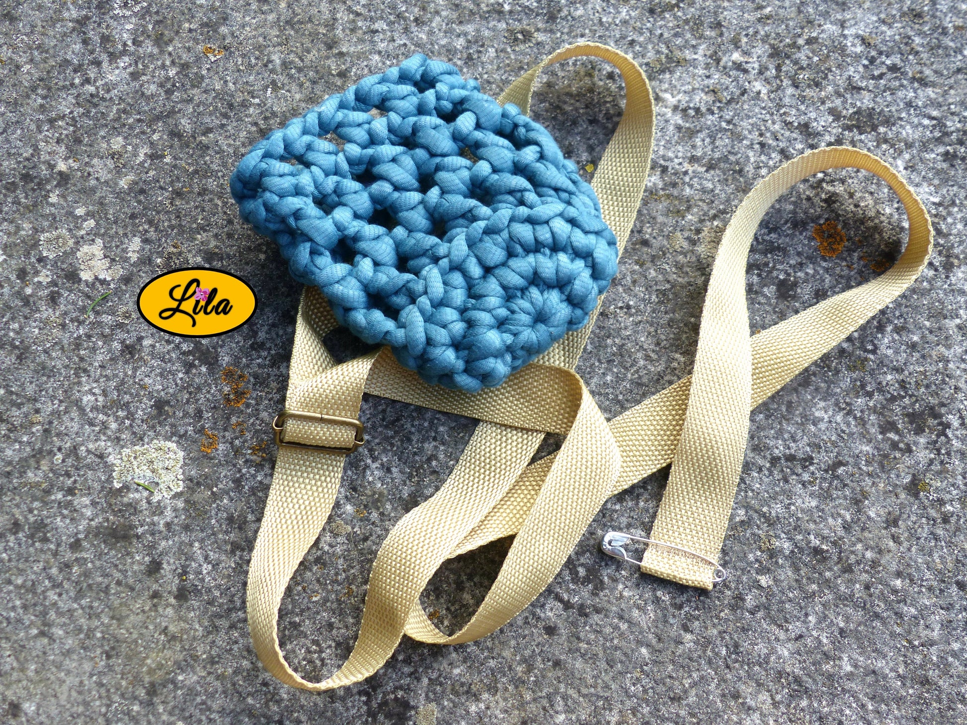 Porte-gobelet crocheté en laine turquoise vu de haut sur une pierre en extérieur avec ceinture sable style artisanal et festival