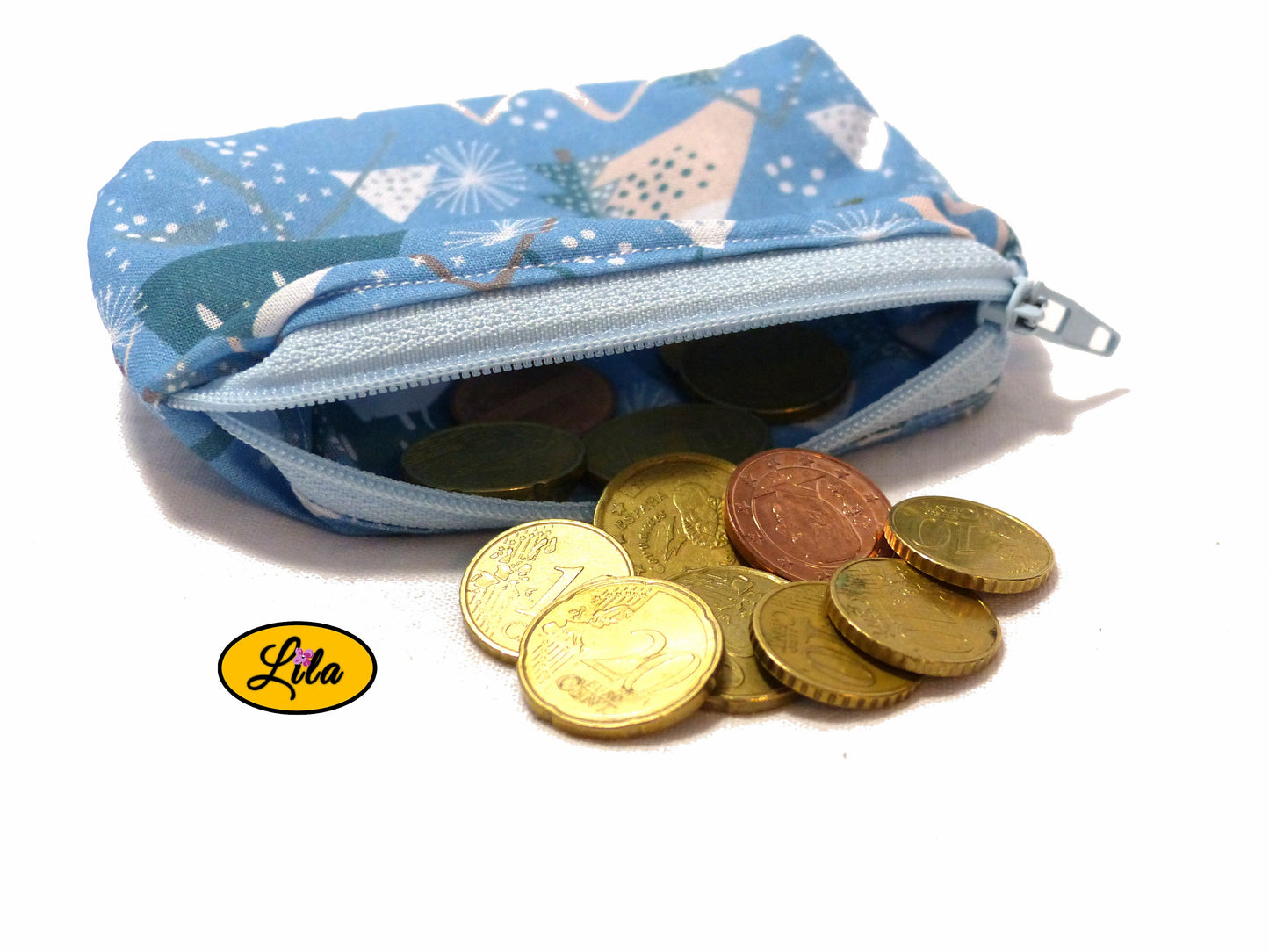 Porte-monnaie en tissu bleu à motifs sapins géométriques ouvert avec pièces de monnaie qui en sortent sur fond blanc style artisanal et fonctionnel