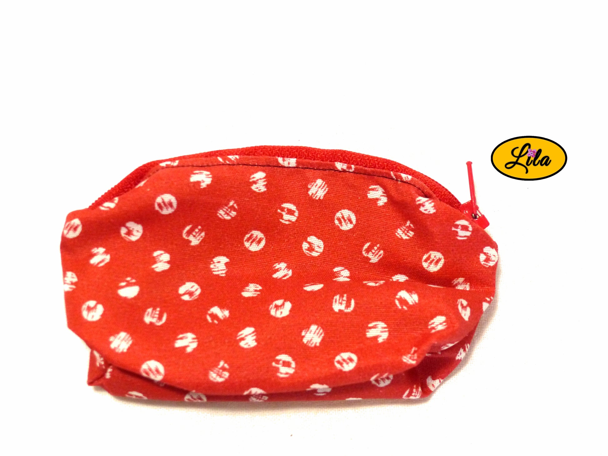 Porte-monnaie en tissu rouge à pois blancs avec fermeture éclair rouge posé de dos sur fond blanc style pin-up et pratique