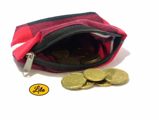 Porte-monnaie en tissu tartan rouge à lignes blanches et noires ouvert avec pièces de monnaie qui en sortent sur fond blanc style artisanal et fonctionnel