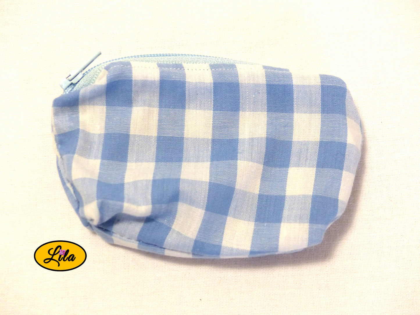Porte-monnaie en tissu vichy bleu et blanc à carreaux avec fermeture éclair bleu ciel posé de face vue de haut sur fond blanc style rétro et artisanal