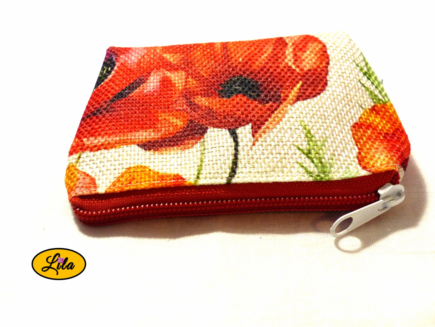Porte-monnaie en tissu vintage à motifs coquelicots avec fermeture éclair rouge et  blanche posé de face avec fermeture visible sur fond blanc style romantique et pratique