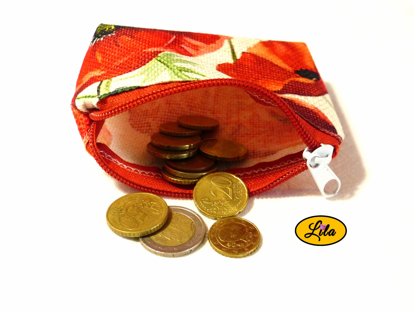 Porte-monnaie en tissu vintage à motifs coquelicots ouvert avec pièces de monnaie qui en sortent sur fond blanc style artisanal et fonctionnel