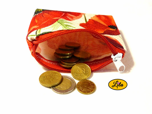 Porte-monnaie en tissu vintage à motifs coquelicots ouvert avec pièces de monnaie qui en sortent sur fond blanc style artisanal et fonctionnel