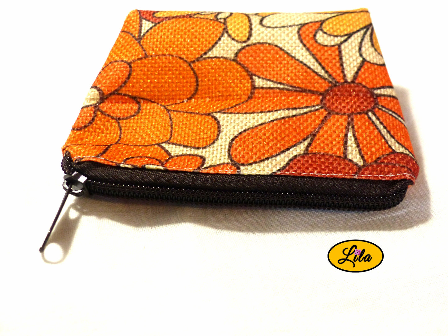 Porte-monnaie en tissu vintage orange fleuri avec fermeture éclair brune posé de face avec fermeture visible sur fond blanc style rétro et pratique