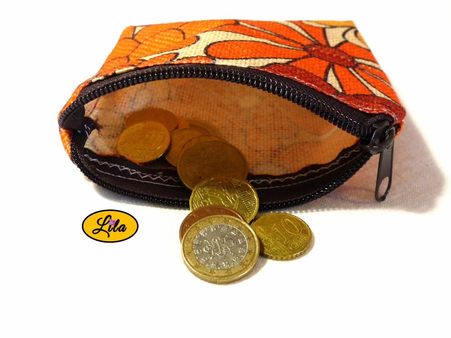 Porte-monnaie en tissu vintage orange fleuri ouvert avec pièces de monnaie qui en sortent sur fond blanc style artisanal et fonctionnel
