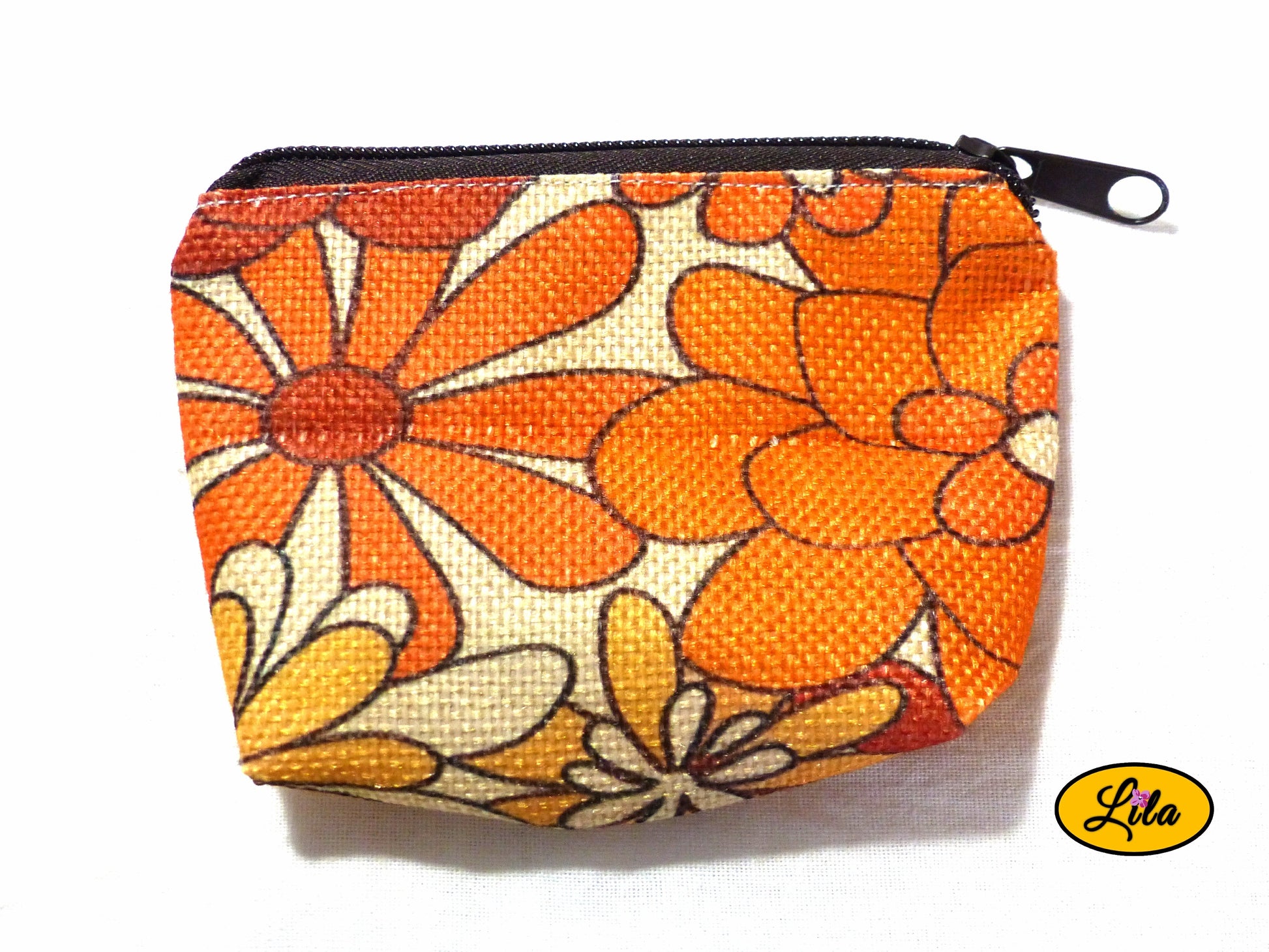 Porte-monnaie en tissu vintage orange fleuri issu d’une ancienne nappe avec fermeture éclair brune posé de face vue de haut sur fond blanc style bohème et artisanal