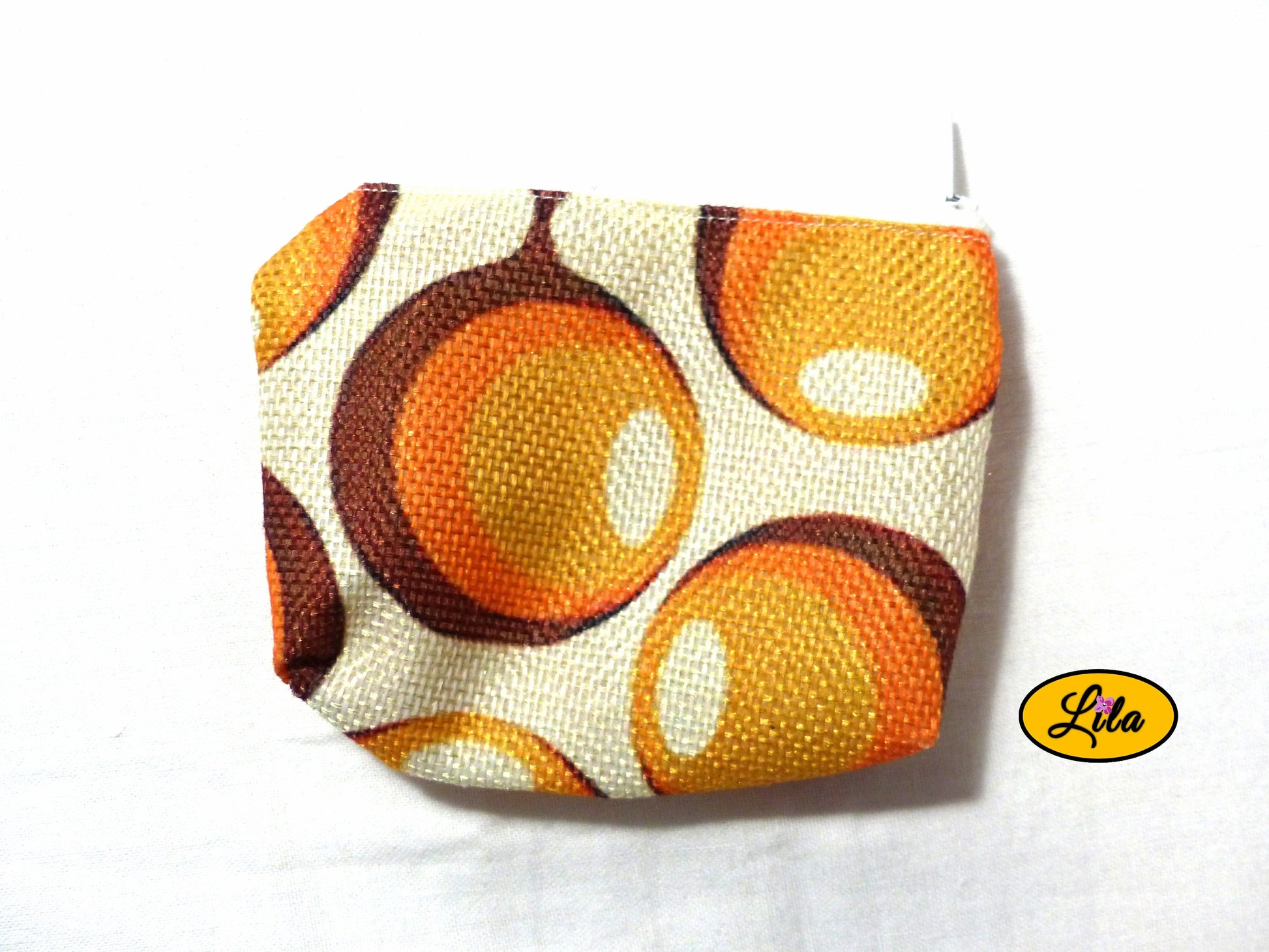 Porte-monnaie en tissu vintage à motifs ronds orange issu d’une ancienne nappe avec fermeture éclair blanche posé de face vue de haut sur fond blanc style rétro et artisanal