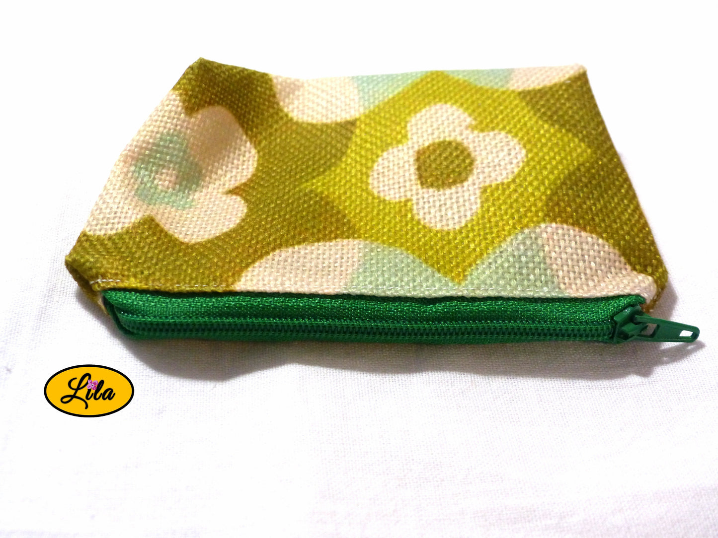 Porte-monnaie en tissu vintage vert fleuri avec fermeture éclair verte posé de face avec fermeture visible sur fond blanc style rétro et pratique