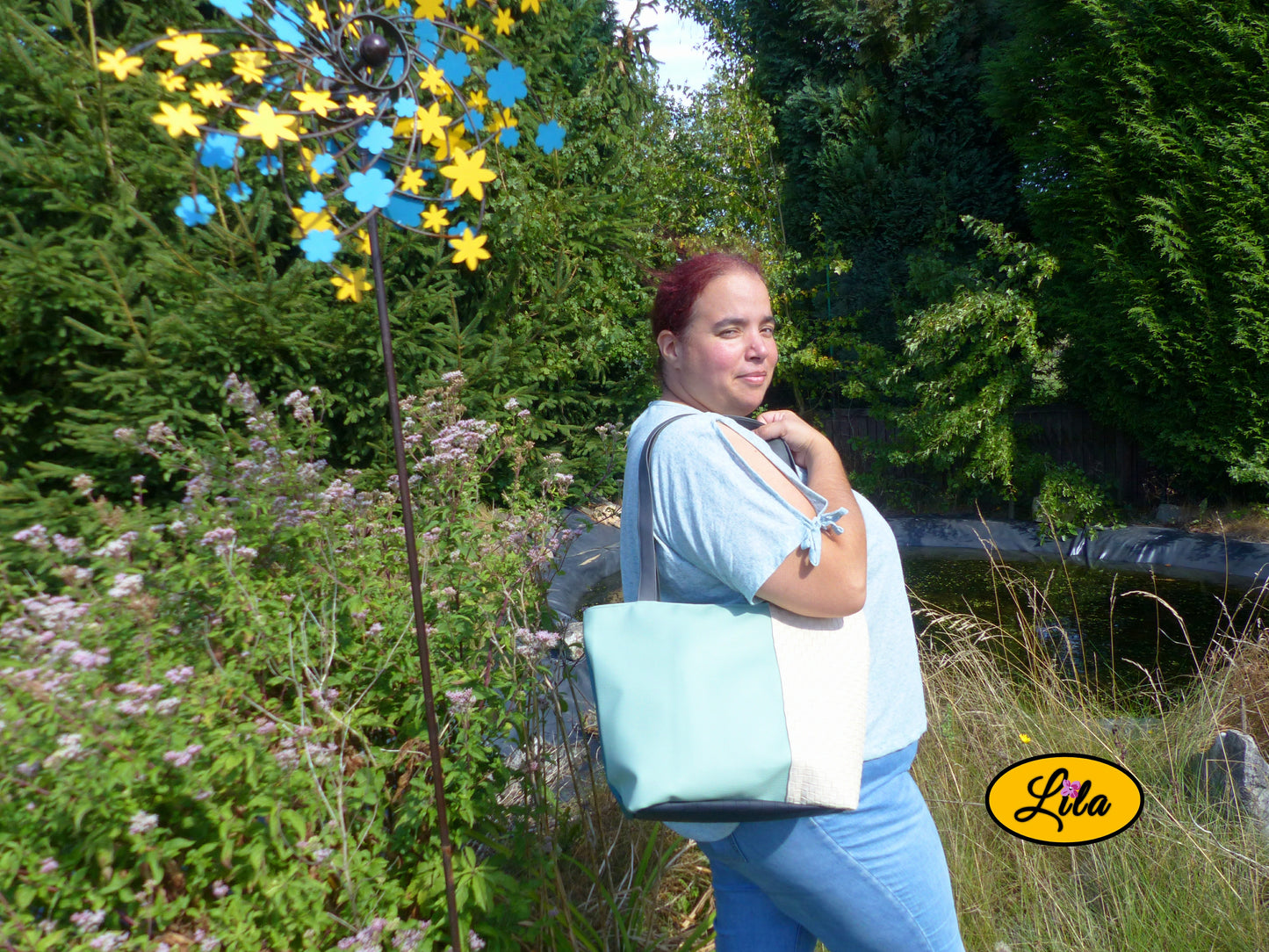 Sac 4 saisons en simili cuir crème et vert porté à l’épaule par une femme en jeans et haut vert devant un étang style chic quotidien