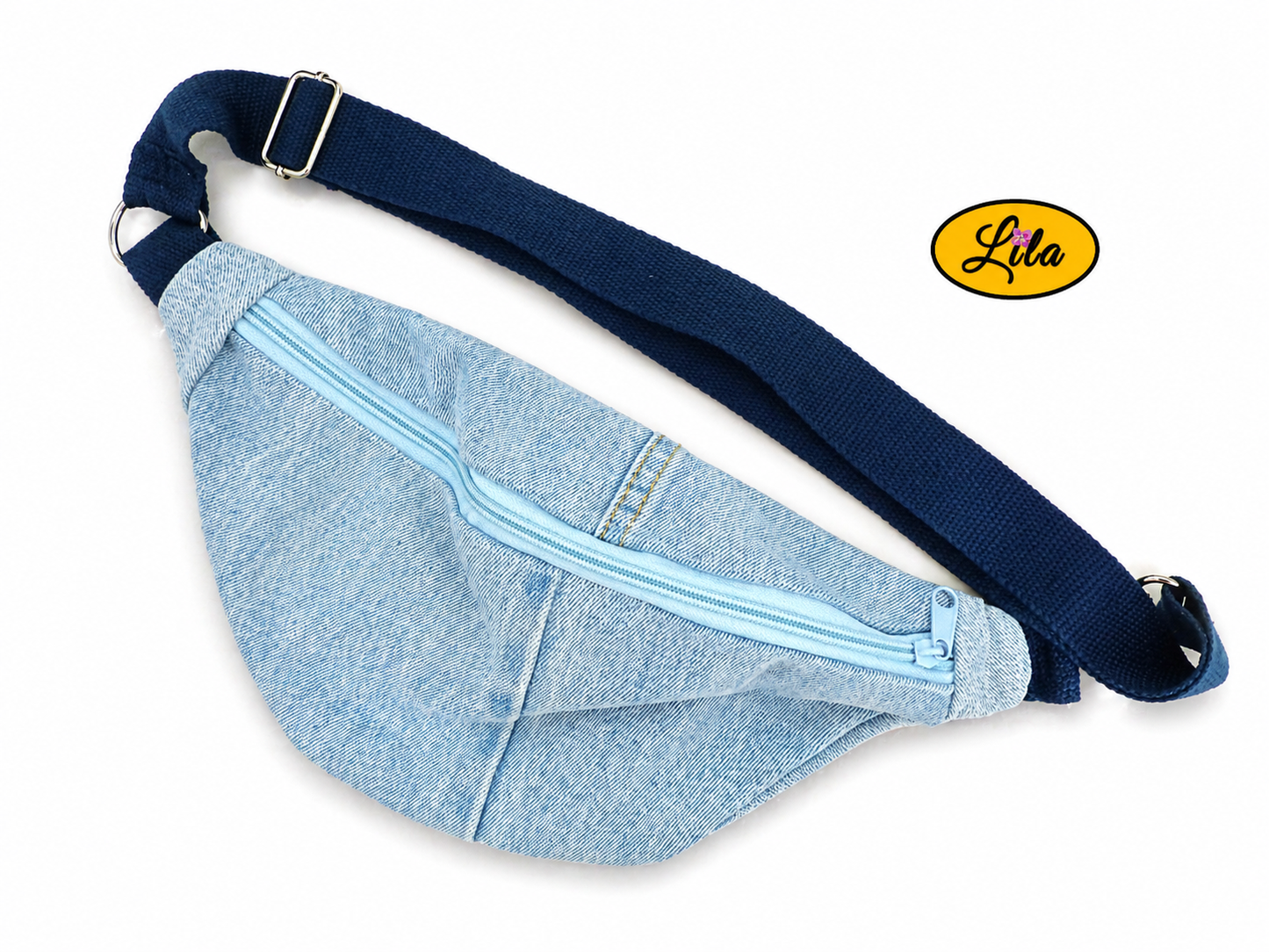Sac banane en jeans clair avec fermeture éclair bleu clair et sangle bleu foncé posé à plat vue de face légèrement pivoté vers la droite avec sangle au-dessus sur fond blanc style casual et moderne