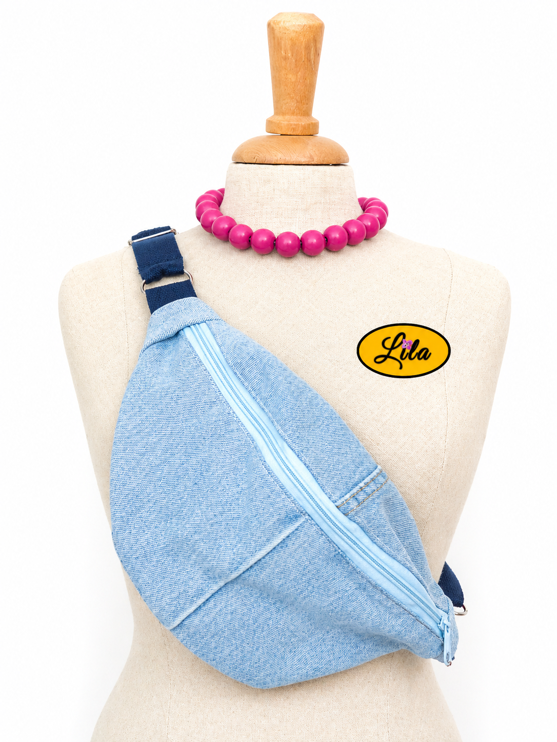 Sac banane en jeans clair avec fermeture éclair bleu clair et sangle bleu foncé porté sur mannequin de couture sur fond blanc style urbain et tendance