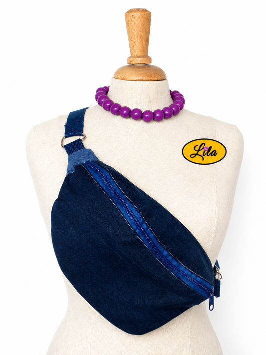 Sac banane en jeans foncé avec fermeture éclair bleu foncé et sangle bleu foncé porté sur mannequin de couture sur fond blanc style urbain et tendance