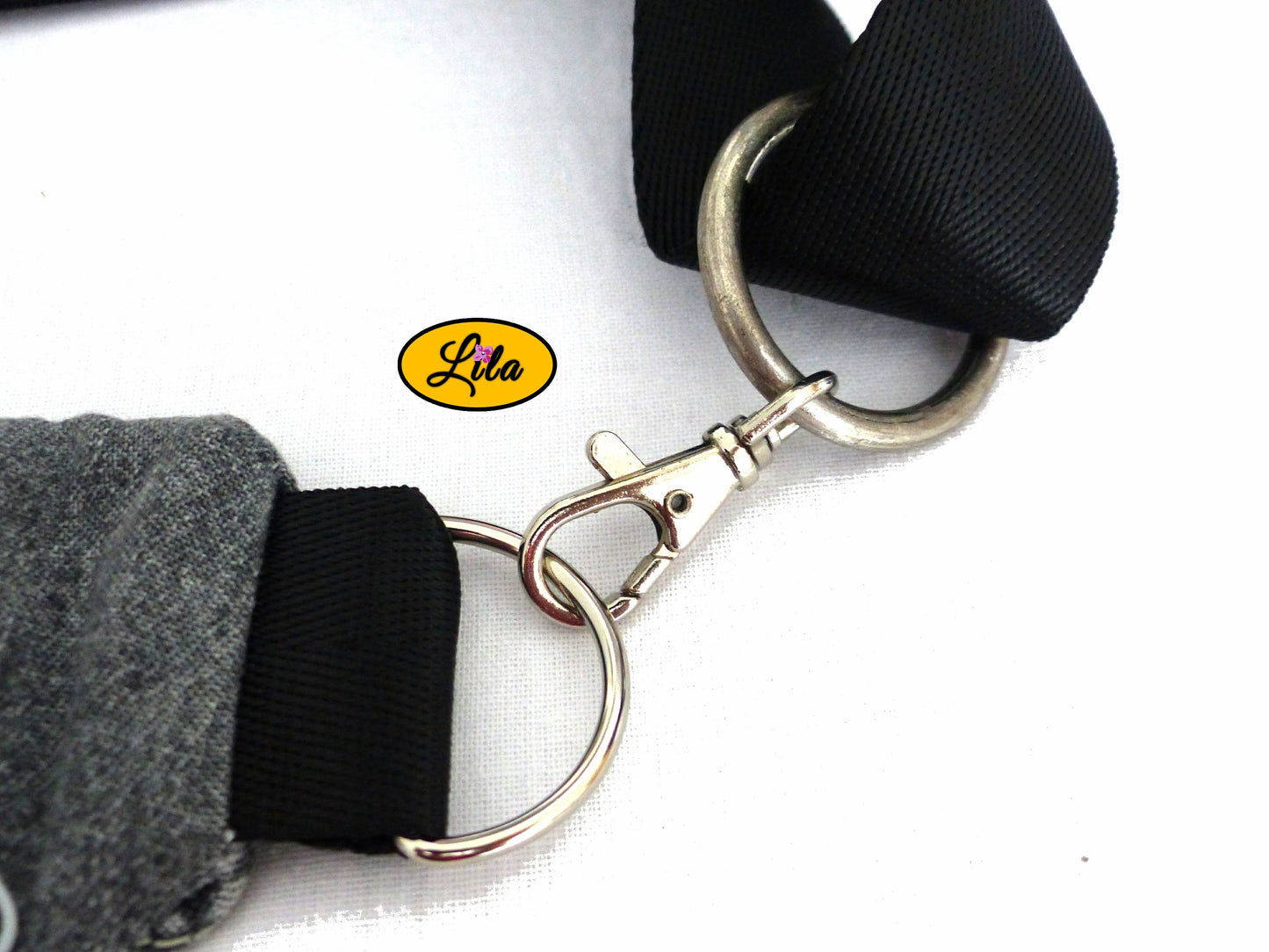 Zoom sur le mousqueton argenté de la sangle attaché à la boucle argentée d’un sac banane en jeans noir style moderne et artisanal