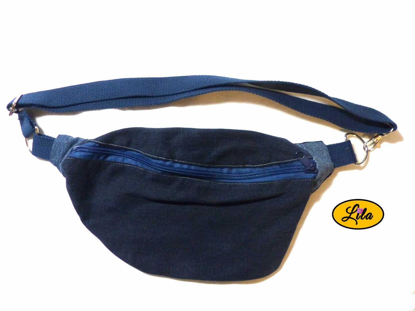 Sac banane en duo de jeans recyclés avec sangle bleue en coton et fermeture éclair bleue posé à plat vue de haut sur fond blanc style upcyclé et tendance