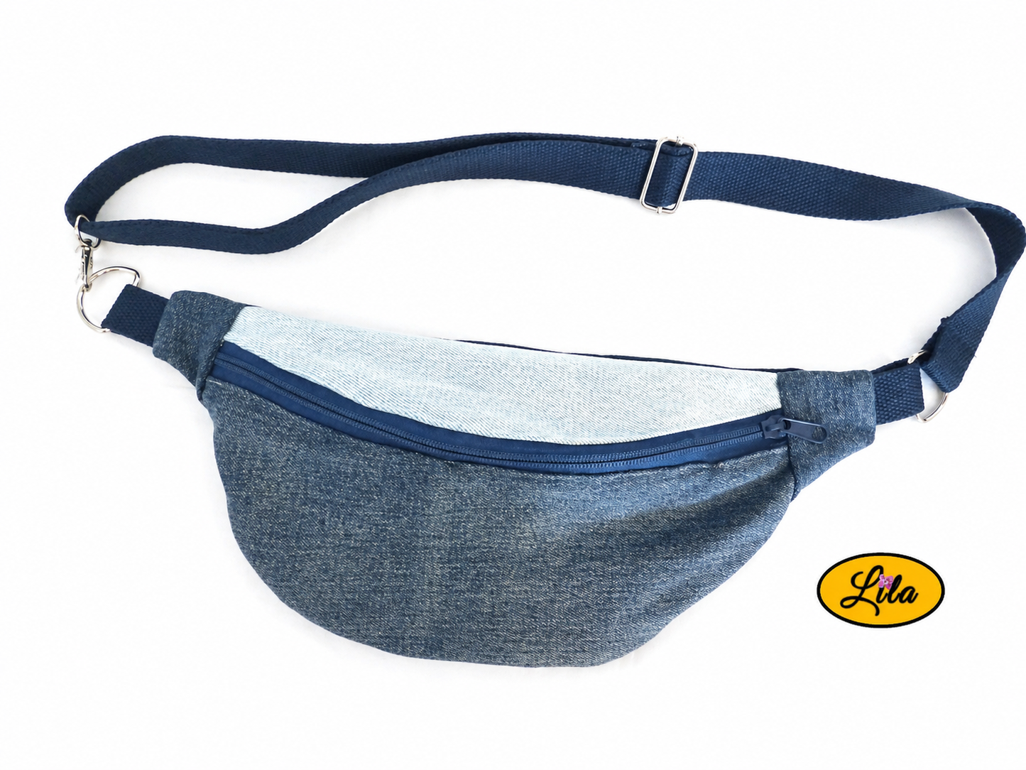 Sac banane en patchwork de jeans recyclés avec sangle bleue et fermeture éclair bleue posé à plat vue de face avec sangle au-dessus sur fond blanc style tendance et upcyclé