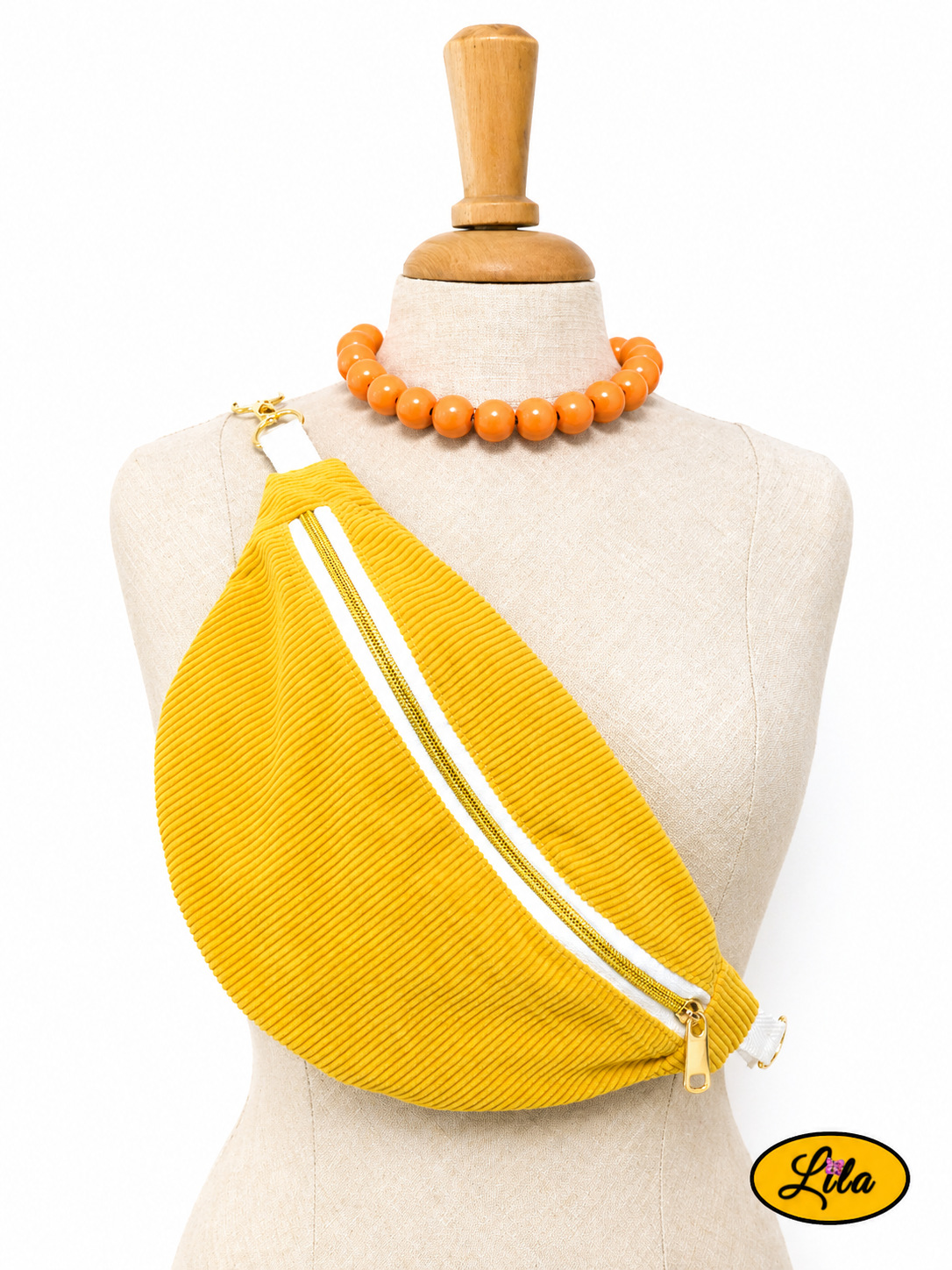 Sac banane en velours côtelé jaune avec sangle blanche fermeture éclair blanche et tirette dorée porté sur mannequin de couture sur fond blanc style tendance et vintage