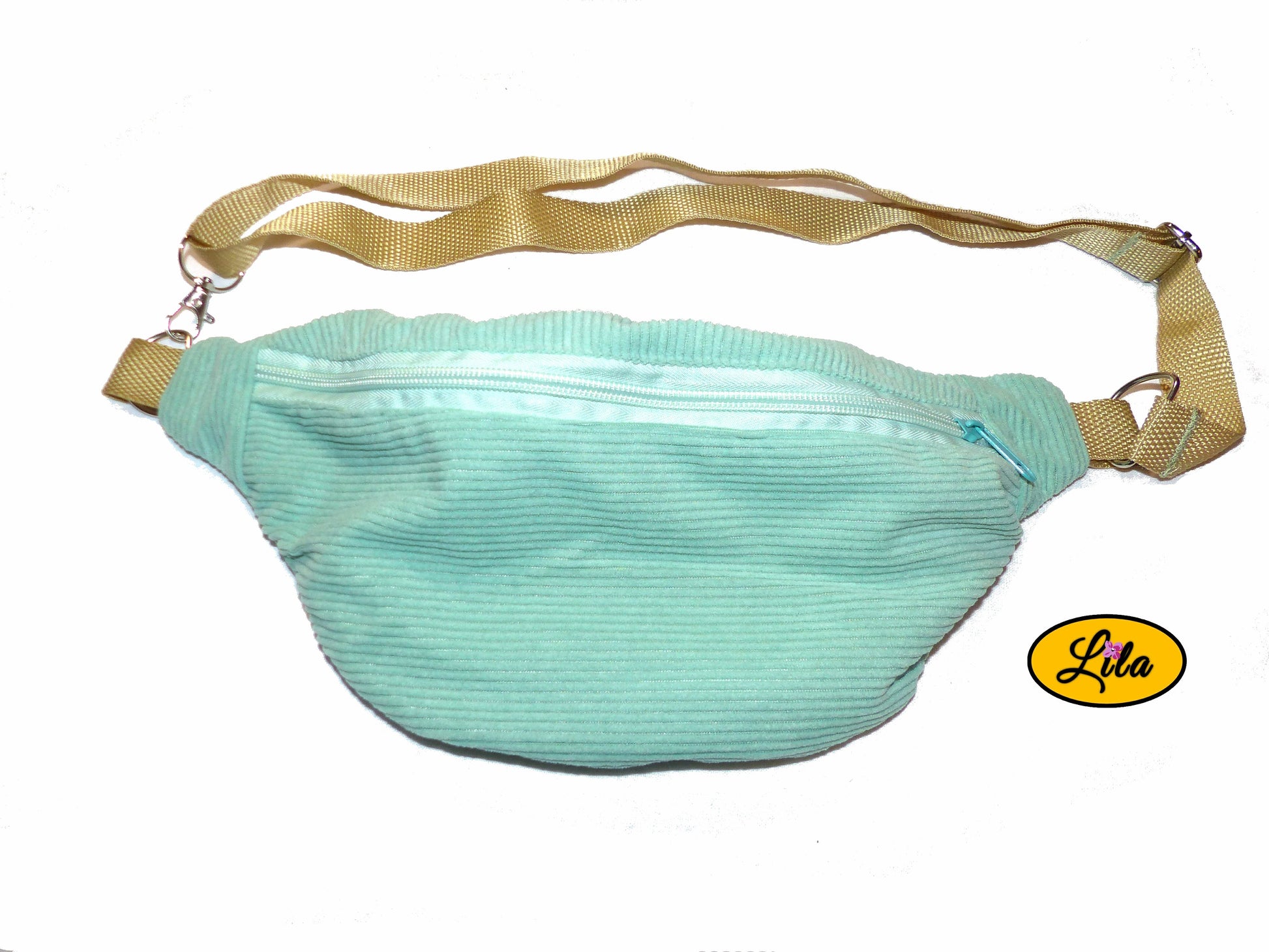Sac banane en velours côtelé vert menthe avec sangle assortie et anse couleur sable posé à plat vue de face sur fond blanc style doux et moderne