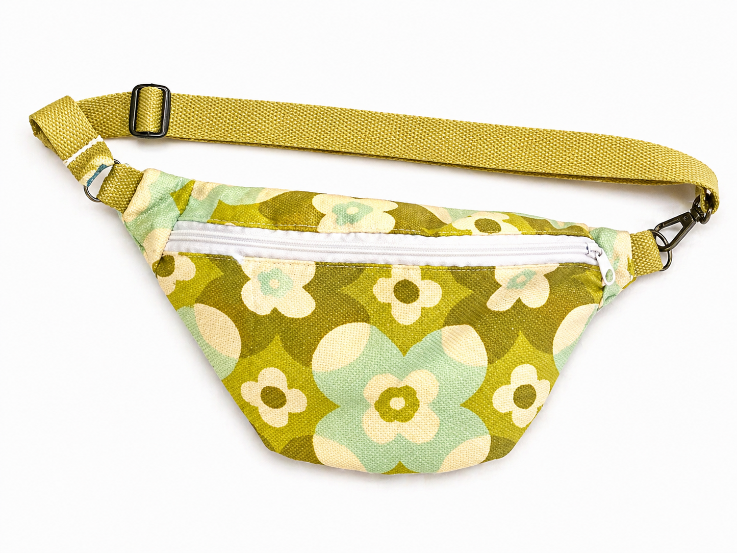 Sac banane vintage fleurie verte avec sangle kaki et fermeture éclair blanche posé à plat vue de face avec sangle au-dessus sur fond blanc style rétro et tendance