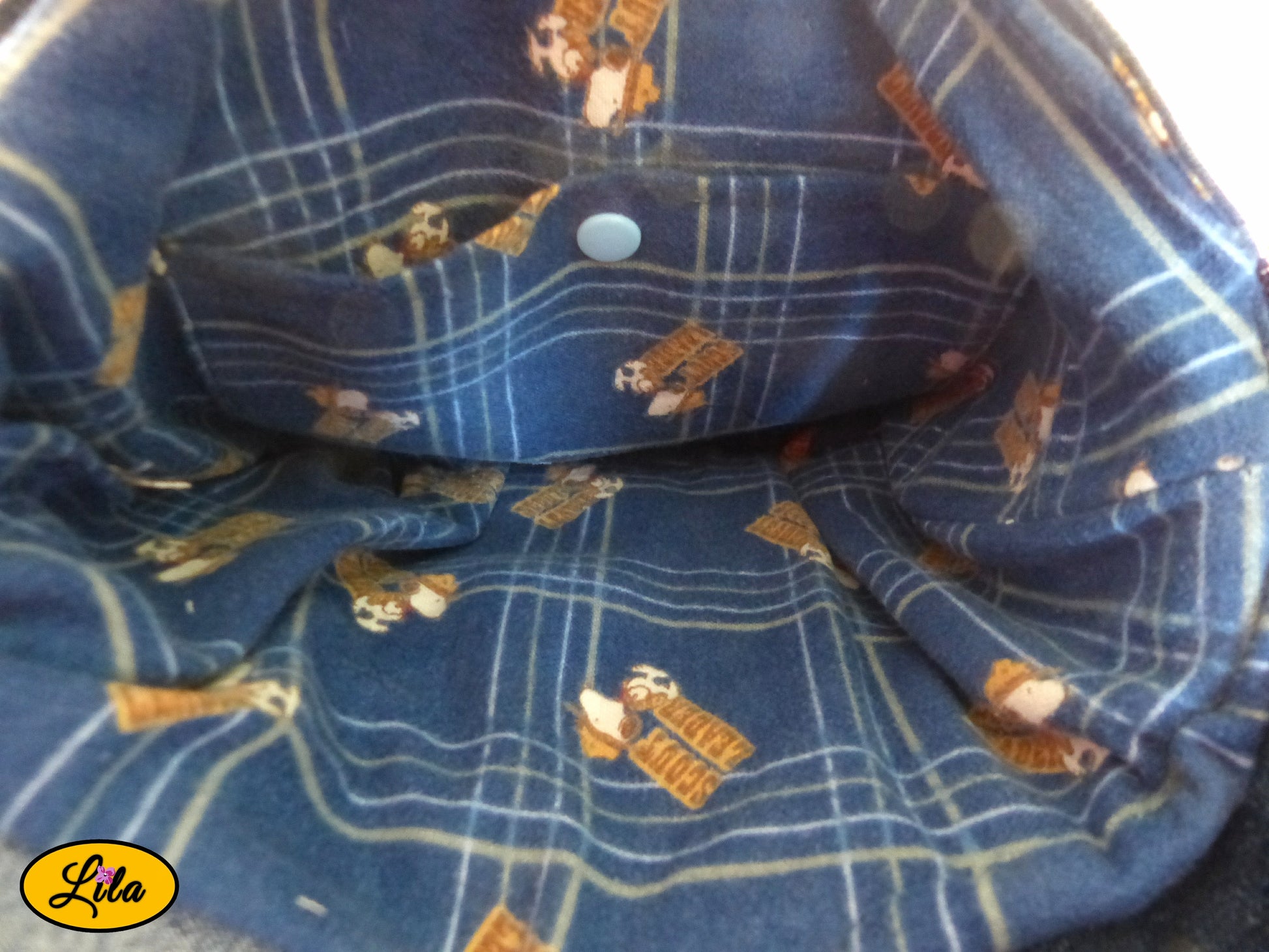 Vue de l'intérieur d'un sac bandoulière en patchwork de jeans recyclés avec doublure bleue à l'effigie de Snoopy cowboy, poche intérieure fermée par une attache pression bleue et finitions artisanales