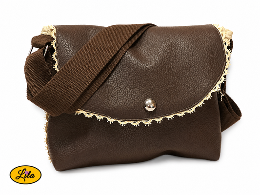 Sac bandoulière en simili cuir brun fermé légèrement de profil droit sur fond blanc avec sangle en coton brun visible et décoration en dentelle crème style artisanal