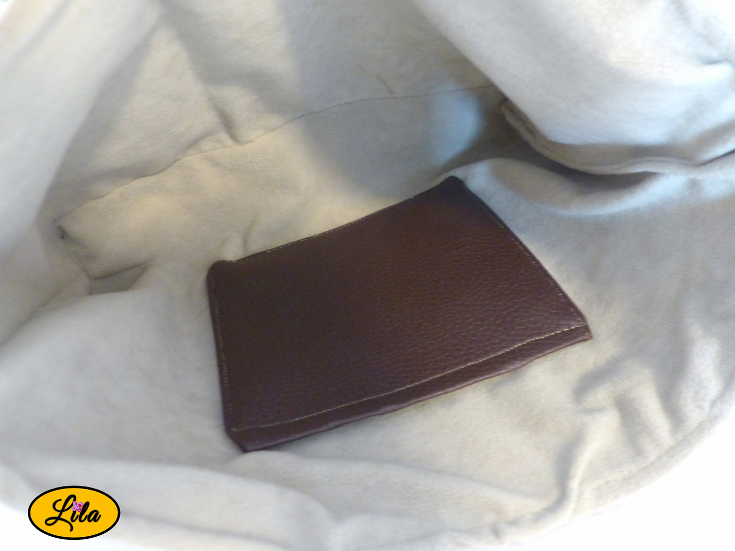 Vue de l'intérieur d'un sac bandoulière en simili cuir brun avec doublure effet chamois, poche intérieure en simili brun et finitions en dentelle crème mettant en valeur le savoir-faire artisanal