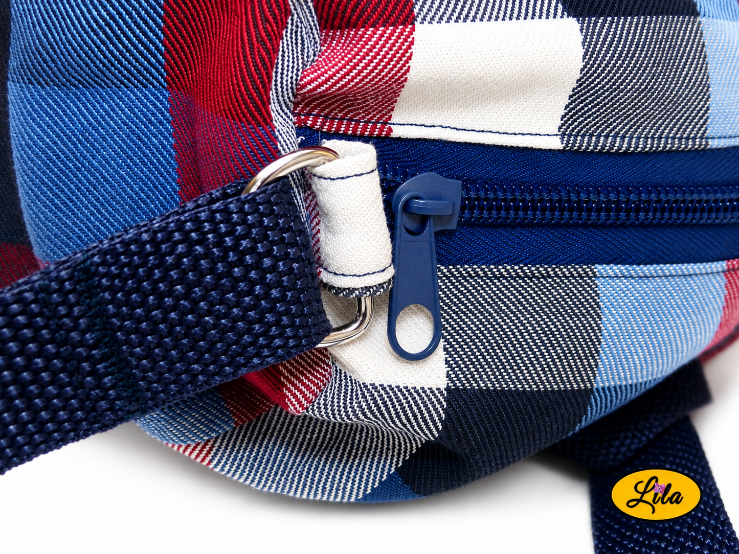 Zoom sur la fermeture éclair et le début de la sangle du sac bandoulière en tartan bleu blanc rouge détail finition et ouverture