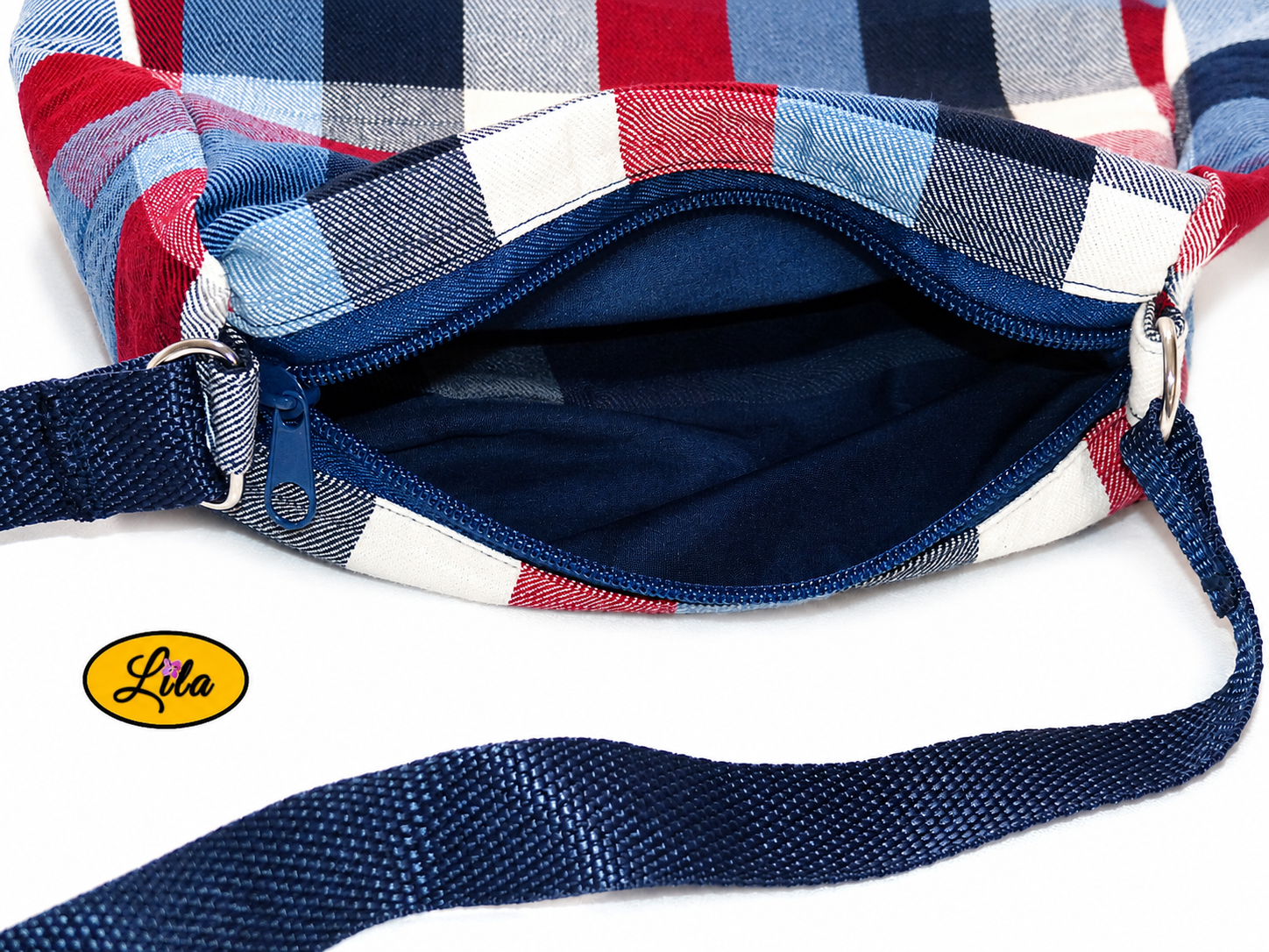 Zoom sur l’ouverture du sac bandoulière en tartan bleu blanc rouge avec aperçu de l’intérieur et détails de finition