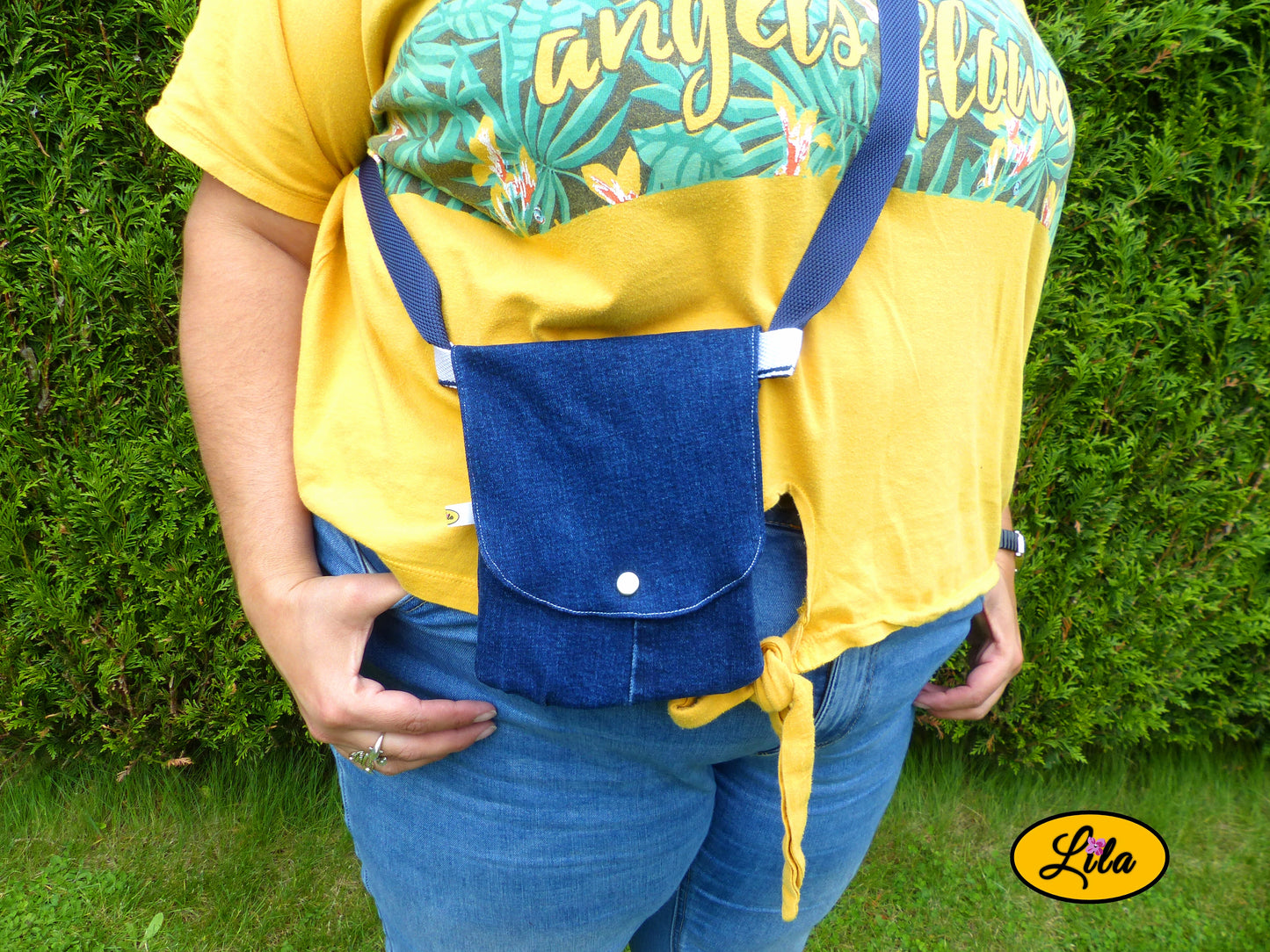 Sac bandoulière pour téléphone en jeans bleu porté par une jeune femme devant une haie dans un jardin avec photo cadrée sur le sac mettant en valeur son format compact et son style artisanal