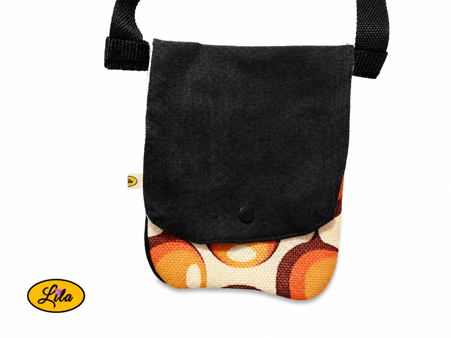 Zoom sur un sac bandoulière pour téléphone en jeans noir avec rabat en ancienne nappe vintage à motifs de ronds orange fermé sans les sangles sur fond blanc mettant en valeur les détails et la fermeture à pression blanche