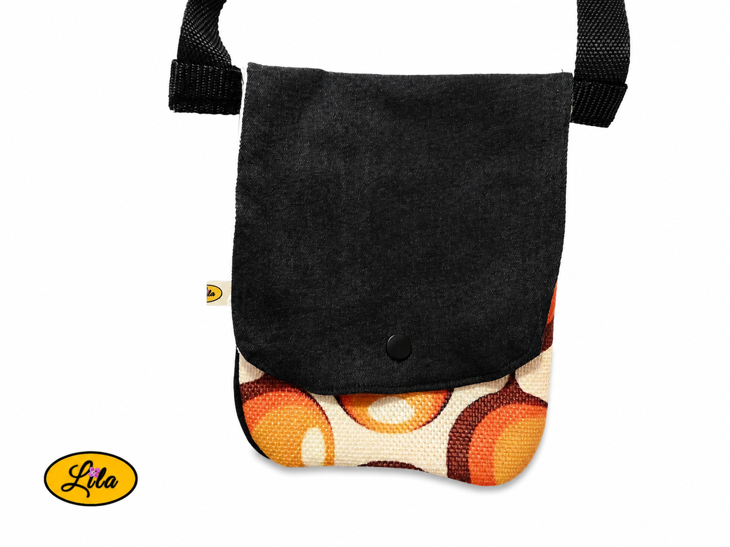 Zoom sur un sac bandoulière pour téléphone en jeans noir avec rabat en ancienne nappe vintage à motifs de ronds orange fermé sans les sangles sur fond blanc mettant en valeur les détails et la fermeture à pression blanche