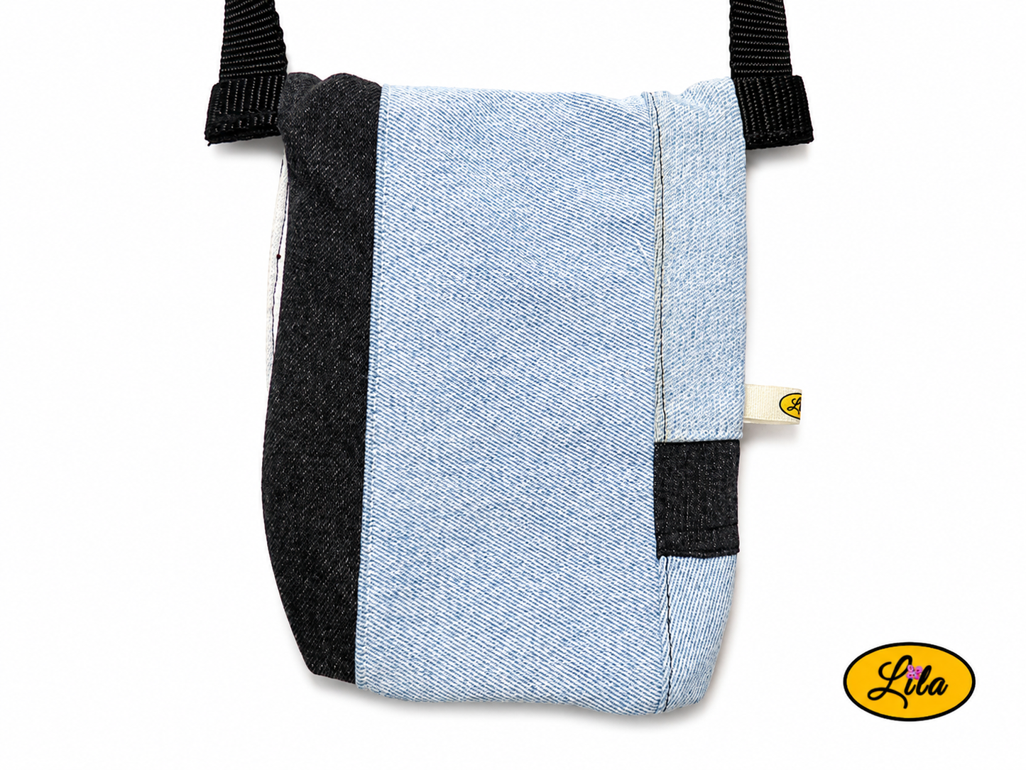 Vue arrière en gros plan d'un sac bandoulière pour téléphone en patchwork de jeans recyclés bleu clair et noir sans les sangles sur fond blanc mettant en valeur les finitions artisanales