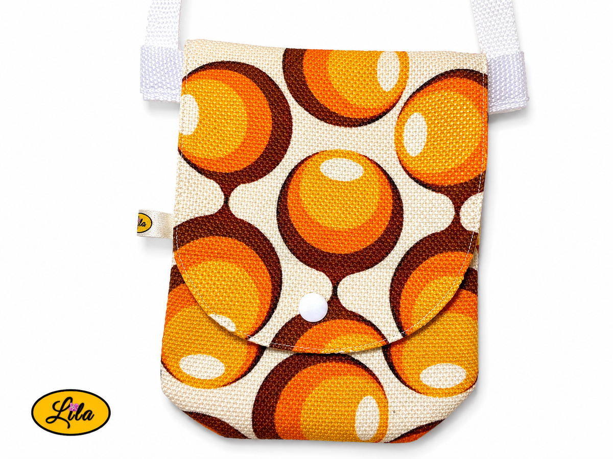 Gros plan sur la pochette de téléphone aux motifs vintage ronds orange et brun avec rabat et bouton pression blanc