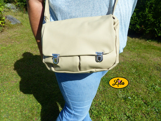 Sac besace en simili blanc crème porté en bandoulière par une femme en extérieur photo cadrée sur le sac style chic et moderne