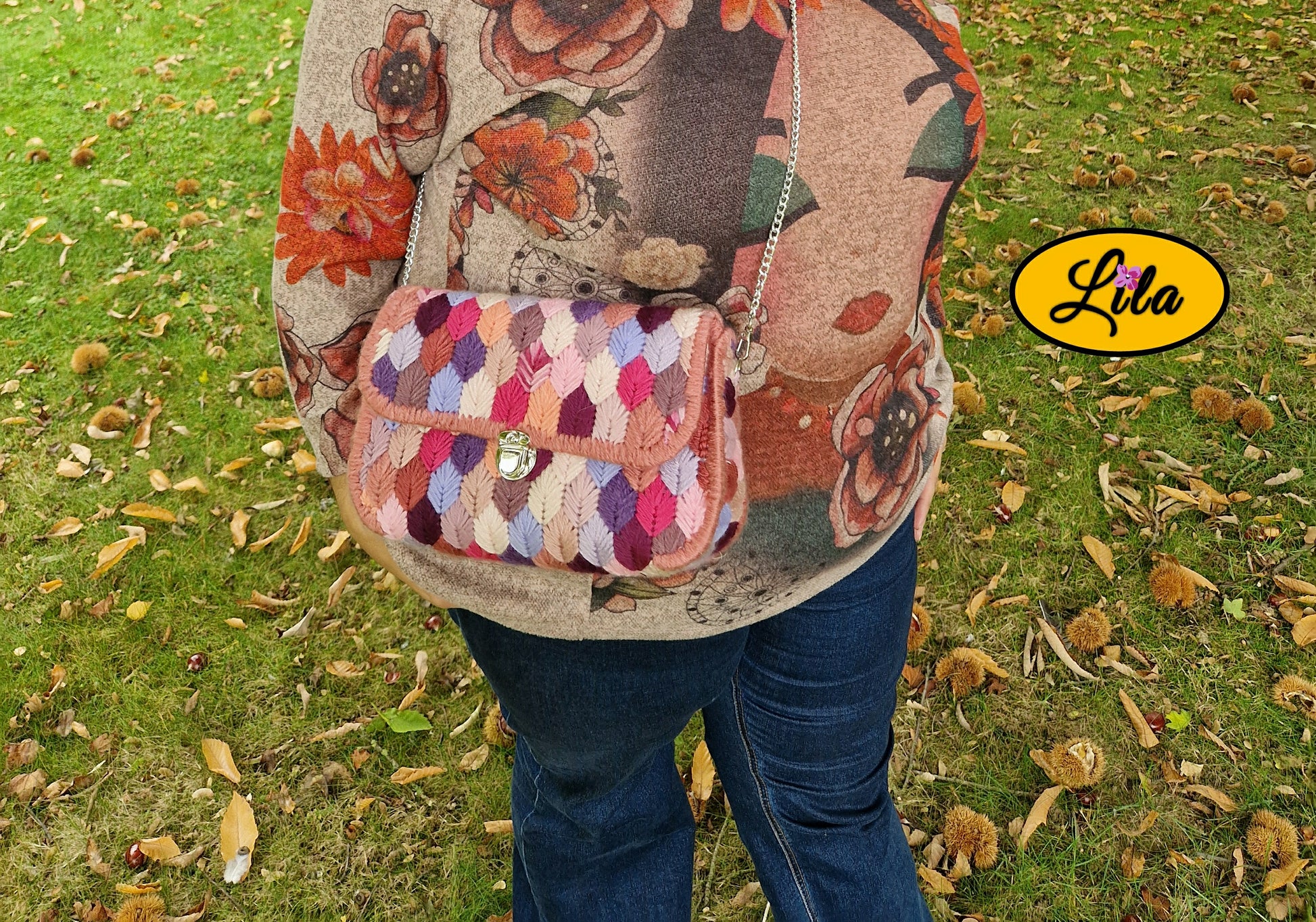 Sac à main aux brins roses sur canevas rigide porté en bandoulière par un mannequin en extérieur automnal photo cadrée sur le sac style original et moderne