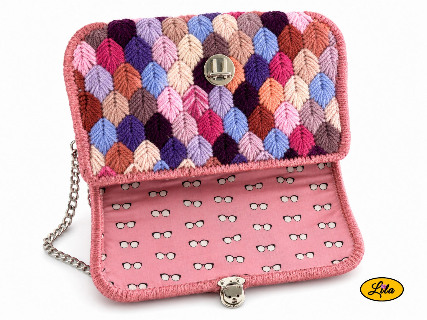 Vue de haut du sac à main aux brins roses ouvert avec doublure rose à motifs yeux, attache cartable argentée et aperçu de la chaîne métallique