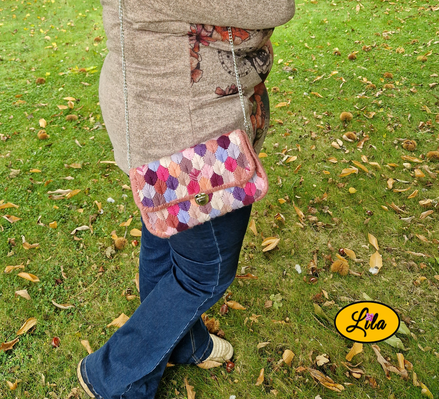 Sac à main aux brins roses sur canevas rigide porté à l’épaule par un mannequin de profil en extérieur automnal photo cadrée sur le sac style créateur et tendance