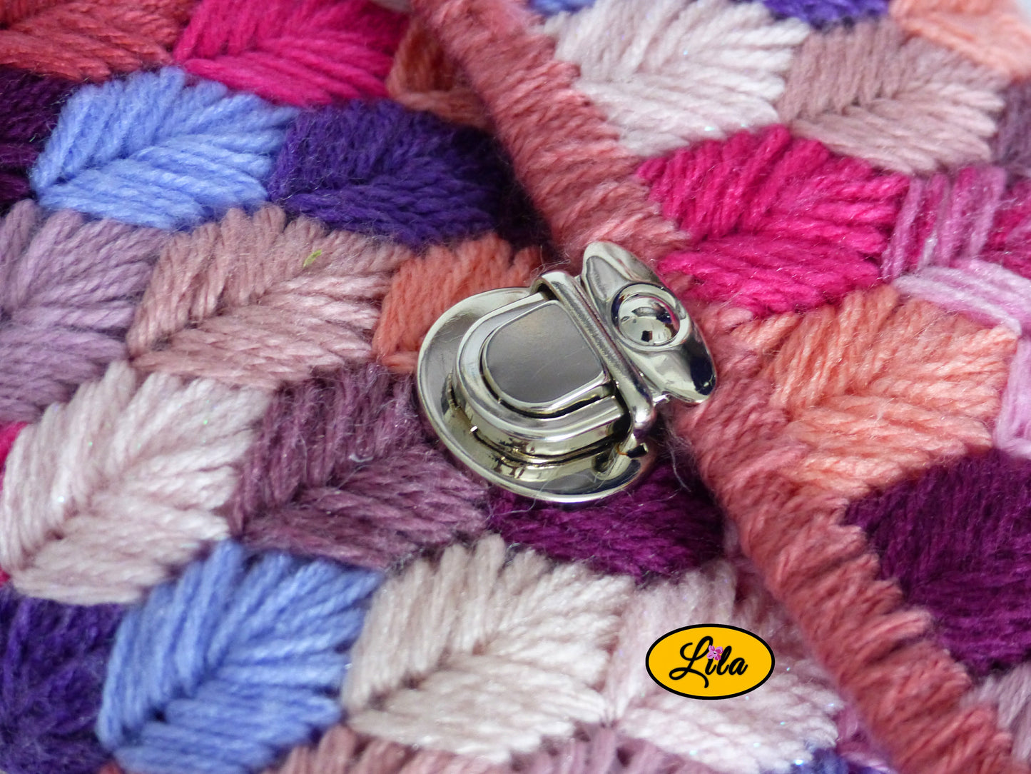 Zoom sur l’attache cartable argentée et les brins roses du sac à main sur canevas rigide détail texture et finition artisanale