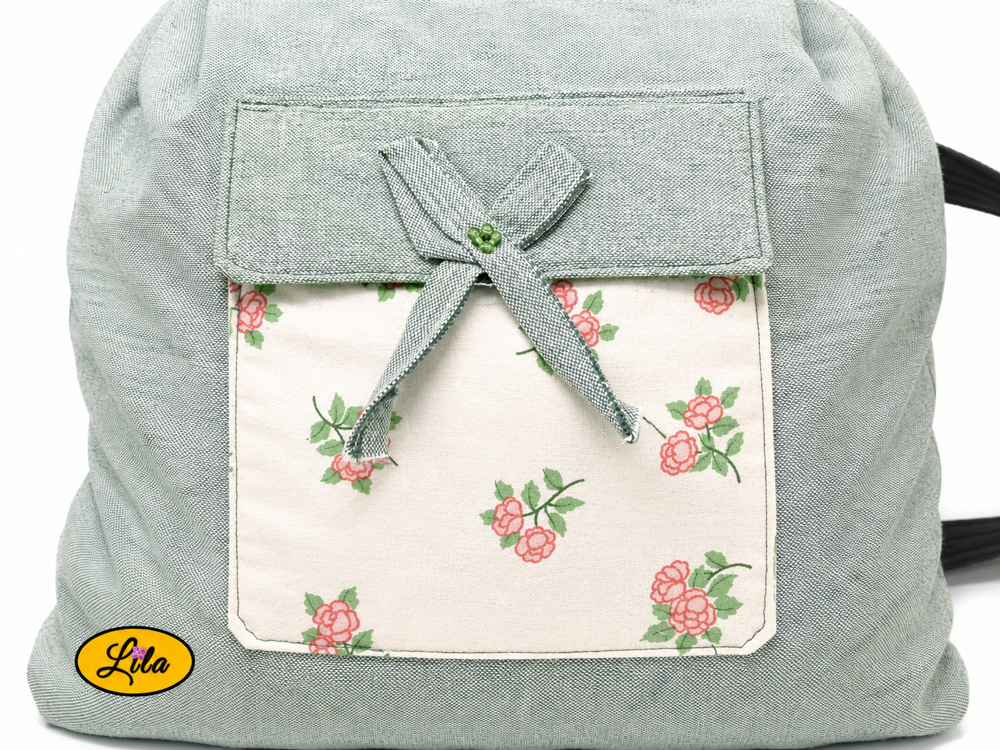 Zoom sur la poche avant du sac à dos vert avec tissu blanc fleuri, fermeture avec petit nœud et détails artisanaux