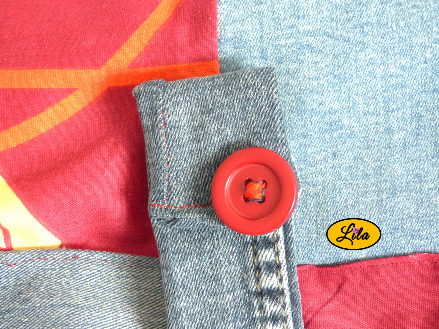 Zoom sur le bouton rouge décoratif du sac épaule en jeans et tissu rouge fleuri recouvrant l’attache pression détail artisanal et fermeture