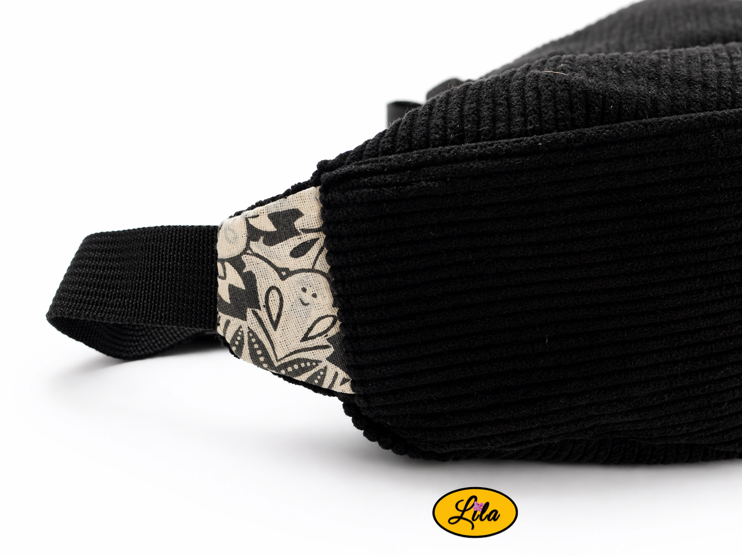 Détail patte sac Luna noir avec anse noire montrant le tissu intérieur blanc à motif noir