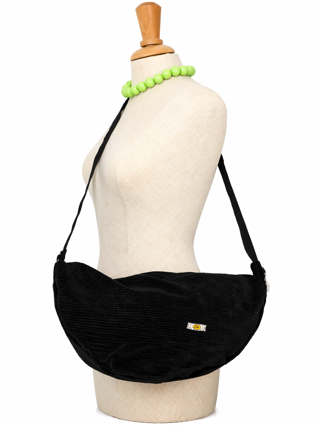 Sac Luna en velours côtelé noir avec anse noire porté sur mannequin de profil montrant la longueur de l’anse