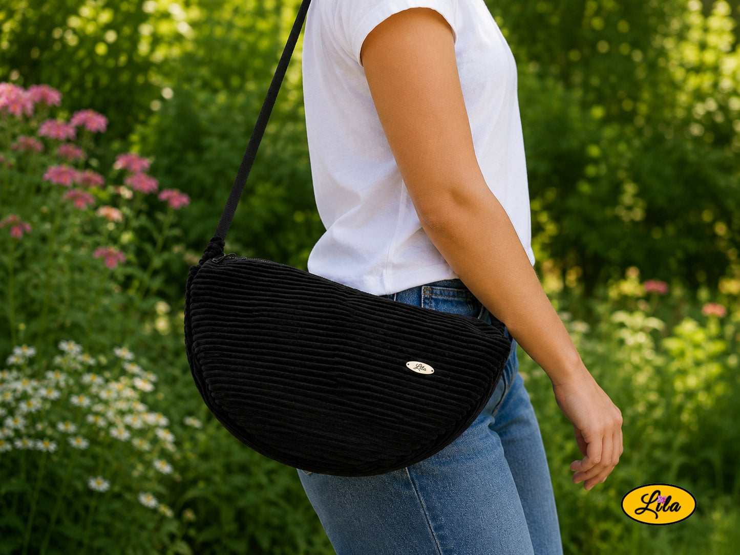 Sac Luna noir en velours côtelé porté à l’épaule par un mannequin en jeans et t-shirt en extérieur photo cadrée sur le sac style urbain et moderne