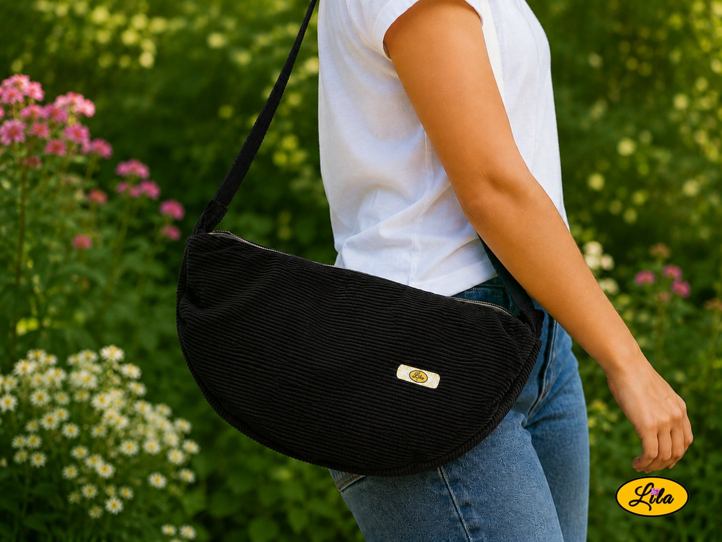 Sac Luna noir en velours côtelé porté à l’épaule par un mannequin en jeans et t-shirt en extérieur photo cadrée sur le sac style urbain et tendance