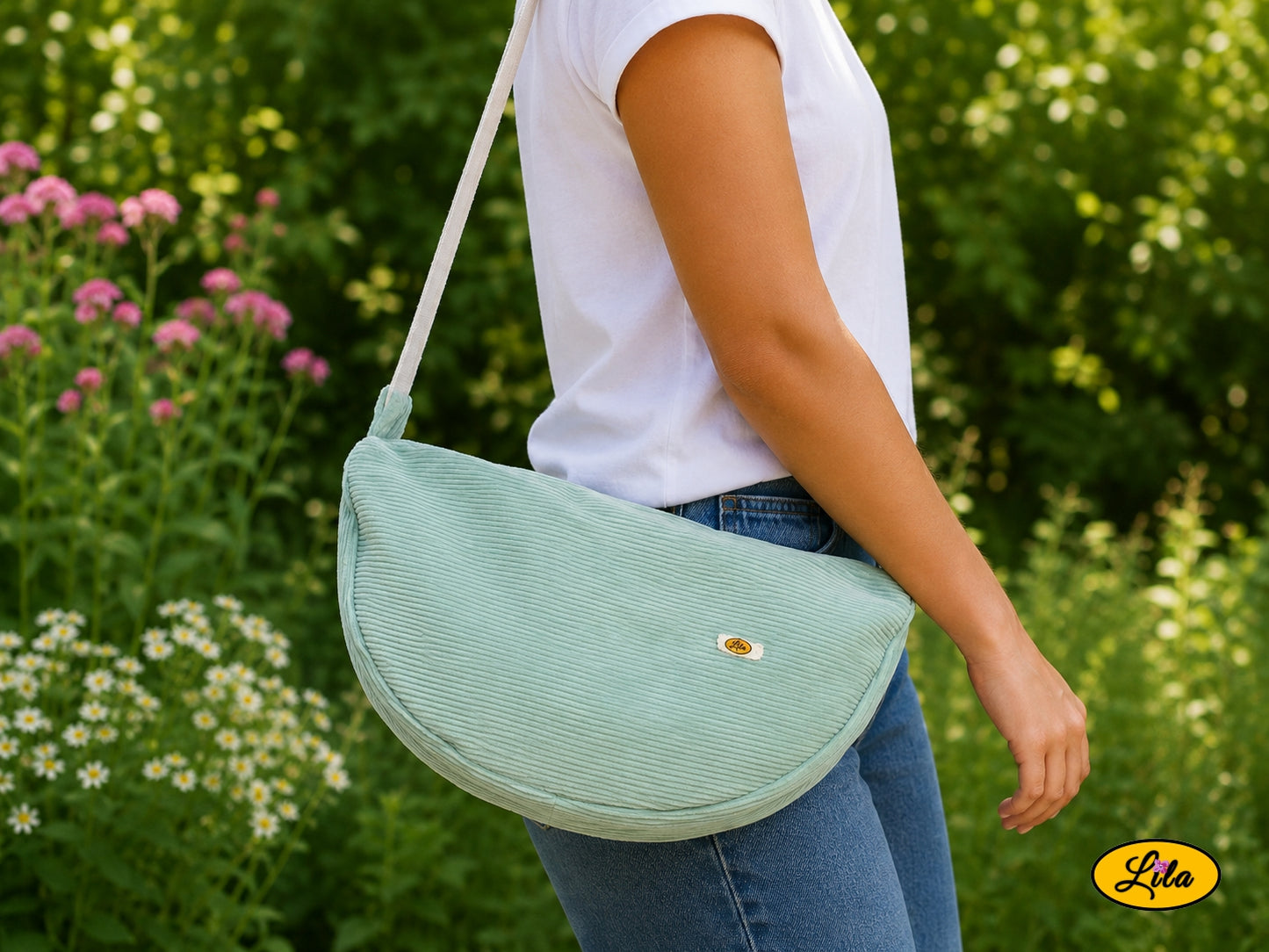 Sac Luna vert menthe en velours côtelé porté à l’épaule par un mannequin en jeans et t-shirt en extérieur photo cadrée sur le sac style moderne et tendance