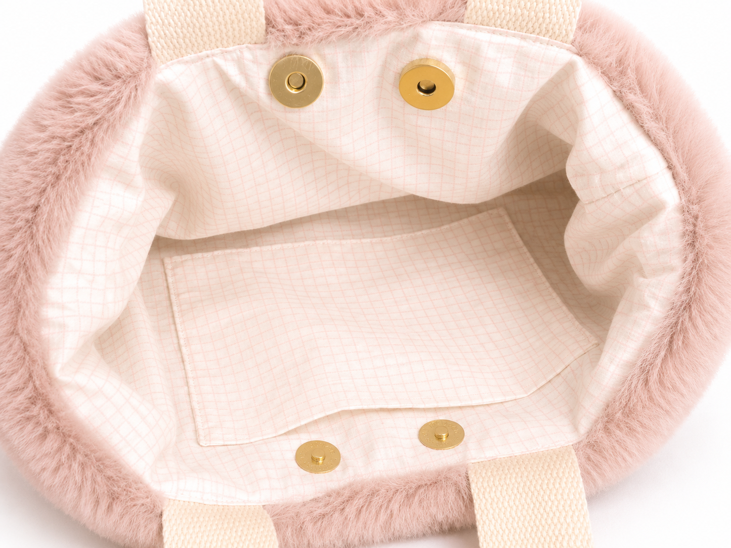Zoom de face du sac à main en fausse fourrure vieux rose ouvert avec doublure blanche quadrillée rose, poche assortie et double fermeture par attache pression sur fond blanc