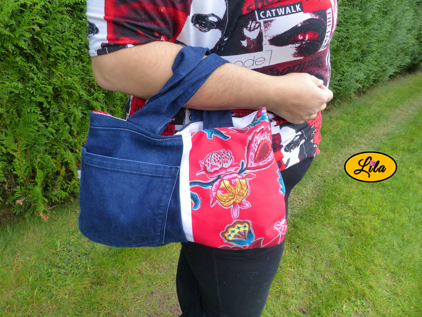 Sac à main en jeans et tissu floral rose porté sur l’avant-bras en extérieur photo cadrée sur le sac style féminin et artisanal