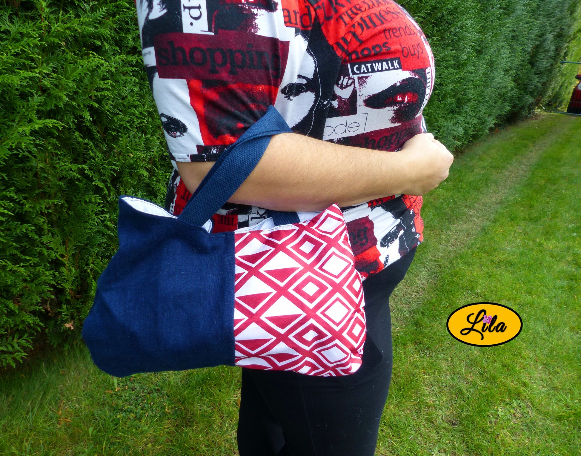 Sac à main en jeans et ancienne nappe rouge et blanche à motifs géométriques porté dans le creux du bras en extérieur photo cadrée sur le sac style rétro et artisanal