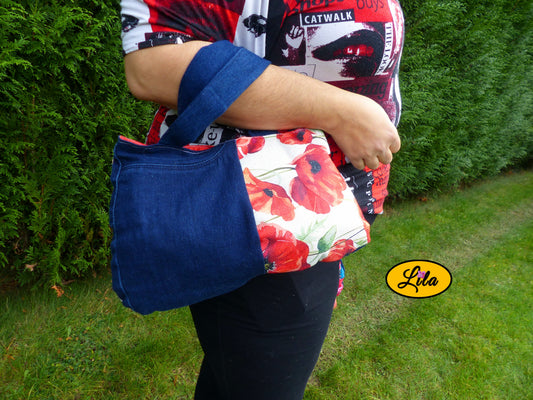 Sac à main en jeans et ancienne nappe vintage motif coquelicot porté sur l’avant-bras en extérieur photo cadrée sur le sac style rétro et artisanal